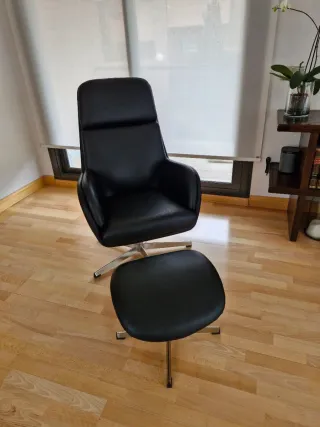 Butaca de piel negra con reposapiés.