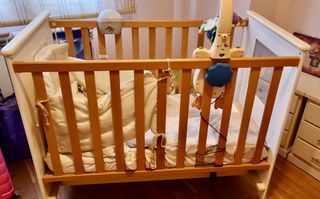 Cuna de madera y blanca de bebé con móvil