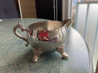 Lechera de metal plateada con patas