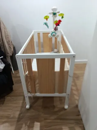 Cuna de bebé con colecho y juguete.