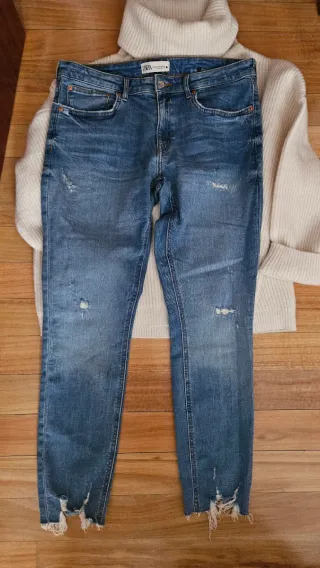 Jersey cuello alto y vaqueros desgastados