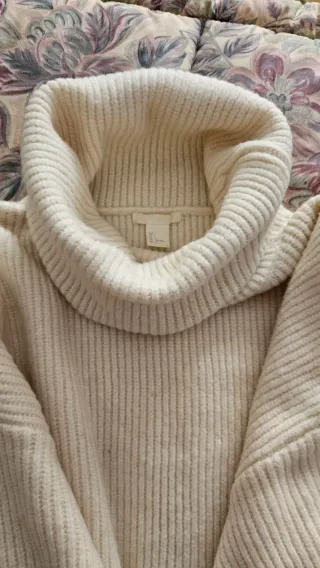 Jersey cuello alto y vaqueros desgastados