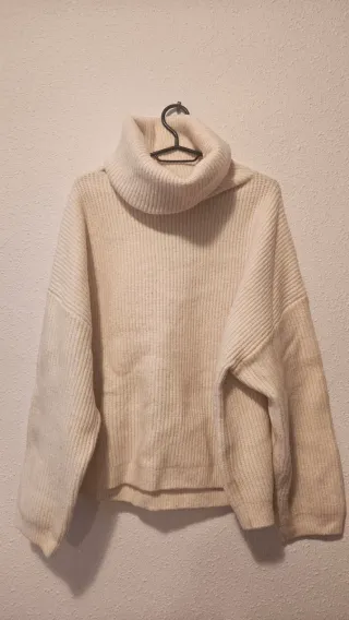 Jersey cuello alto y vaqueros desgastados