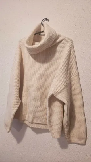 Jersey cuello alto y vaqueros desgastados