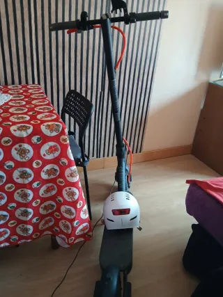 Patinete eléctrico negro con casco blanco