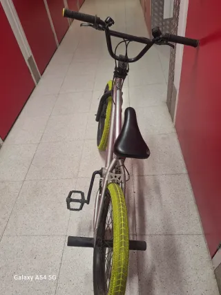 Bicicleta BMX plateada con ruedas amarillas