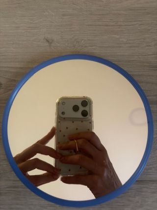 Espejo de mano con aumento por un lado.