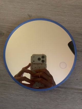 Espejo de mano con aumento por un lado.