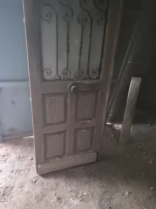 Puerta de madera con reja y tirador  muy robusta .