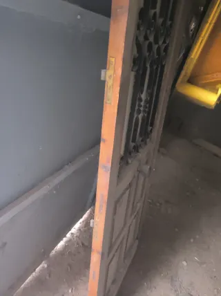 Puerta de madera con reja y tirador  muy robusta .