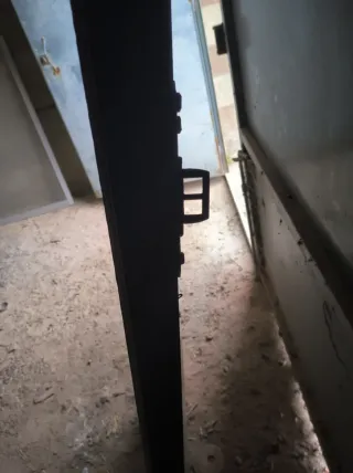 Puerta de madera con reja y tirador  muy robusta .