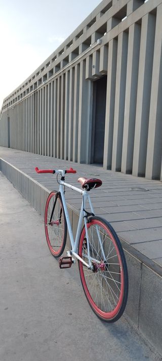 Bicicleta estilo Fixie blanca con ruedas rojas