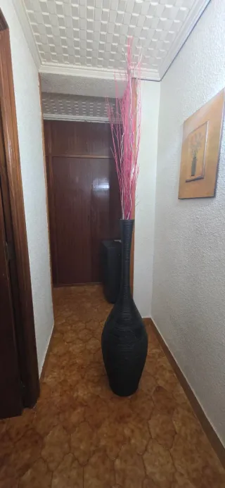 Jarrón de mimbre negro con ramas rosas