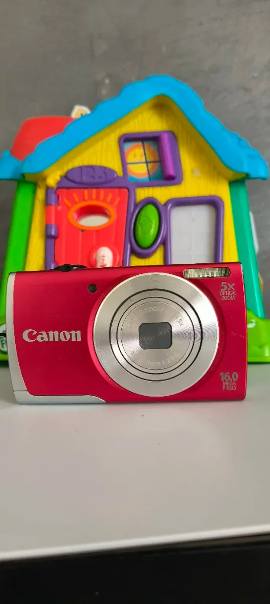 Cámara digital compacta roja con algunos arañazos pero totalmente funcional