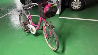 Bicicletta rosa con cestino, lucchetto e casco