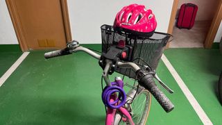 Bicicletta rosa con cestino, lucchetto e casco