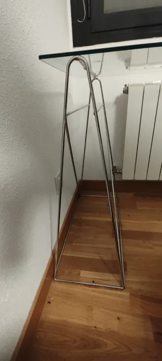 Mesa escritorio de cristal con soportes de metal.