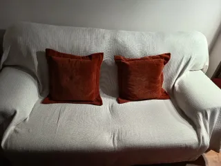 Sofá de tela beige con cojines naranjas