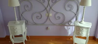 Cabecero de forja blanco, mesillas, lámpara techo.