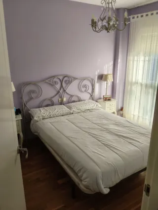 Cabecero de forja blanco, mesillas, lámpara techo.