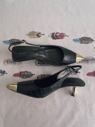 Tacones negros elegantes con punta dorada