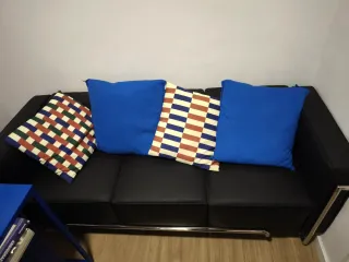 Sofá de piel negro con cojines azules