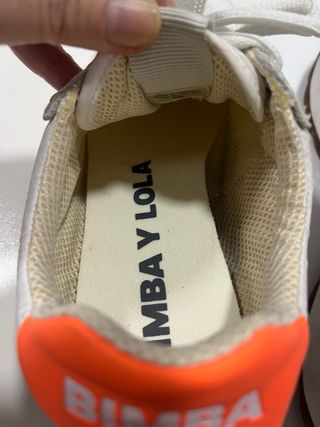 Zapatillas Bimba y Lola blancas y logo naranja.