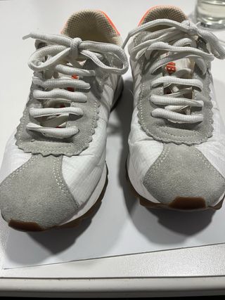 Zapatillas Bimba y Lola blancas y logo naranja.