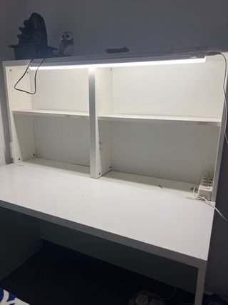 Escritorio blanco con estanterías y luz.