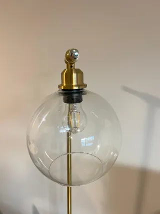 Lámpara de pie dorada con globo de cristal