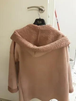 Chaqueta rosa con capucha y cremallera. Es amplia
