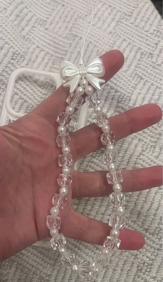 Funda iPhone 15 Pro con colgante de perlas.