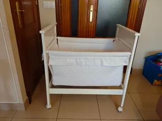Minicuna blanca de madera con ruedas.