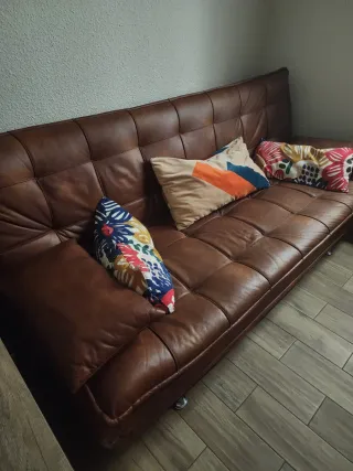 Sofá de piel marrón con cojines