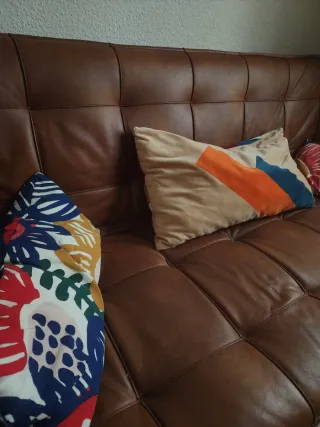 Sofá de piel marrón con cojines