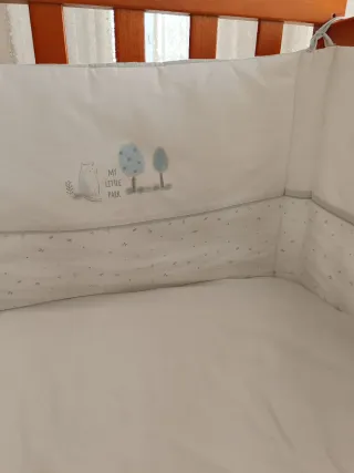 Protector de cuna blanco con dibujos.