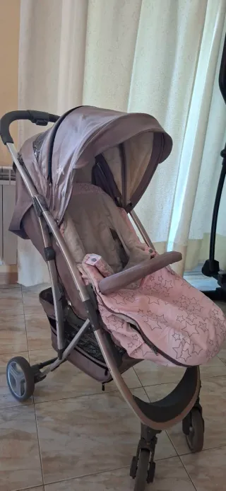 Coche de bebé gris con saco rosa