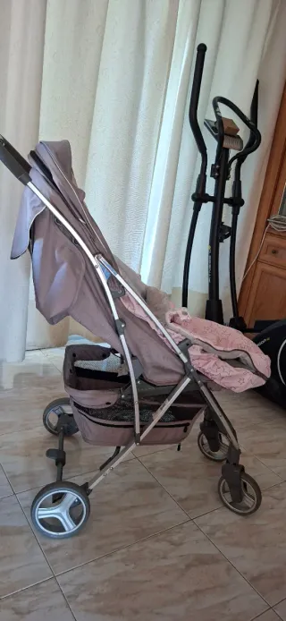 Coche de bebé gris con saco rosa