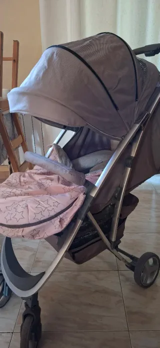 Coche de bebé gris con saco rosa