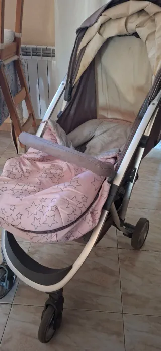 Coche de bebé gris con saco rosa