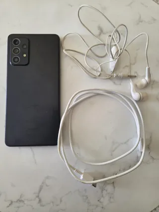 Móvil negro con auriculares y cargador