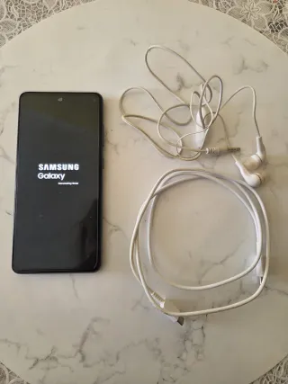 Móvil negro con auriculares y cargador