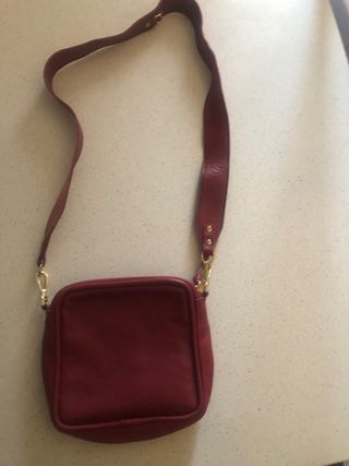 Bolso bandolera granate de piel con flecha dorada.