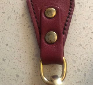 Bolso bandolera granate de piel con flecha dorada.