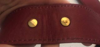 Bolso bandolera granate de piel con flecha dorada.