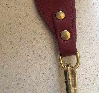 Bolso bandolera granate de piel con flecha dorada.