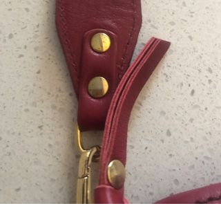 Bolso bandolera granate de piel con flecha dorada.