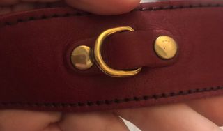 Bolso bandolera granate de piel con flecha dorada.