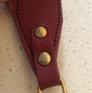 Bolso bandolera granate de piel con flecha dorada.