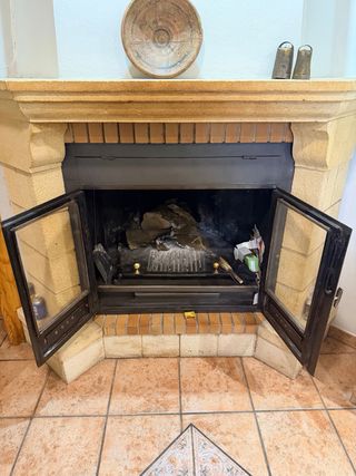 Chimenea de piedra natural y metal esquinada.